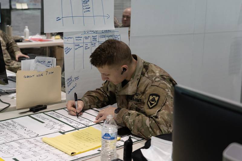 A West Virginia National Guardsman writes on a poster board inside the state's joint interagency task force for the Covid-19 Vaccine. Willy Lowry / The National