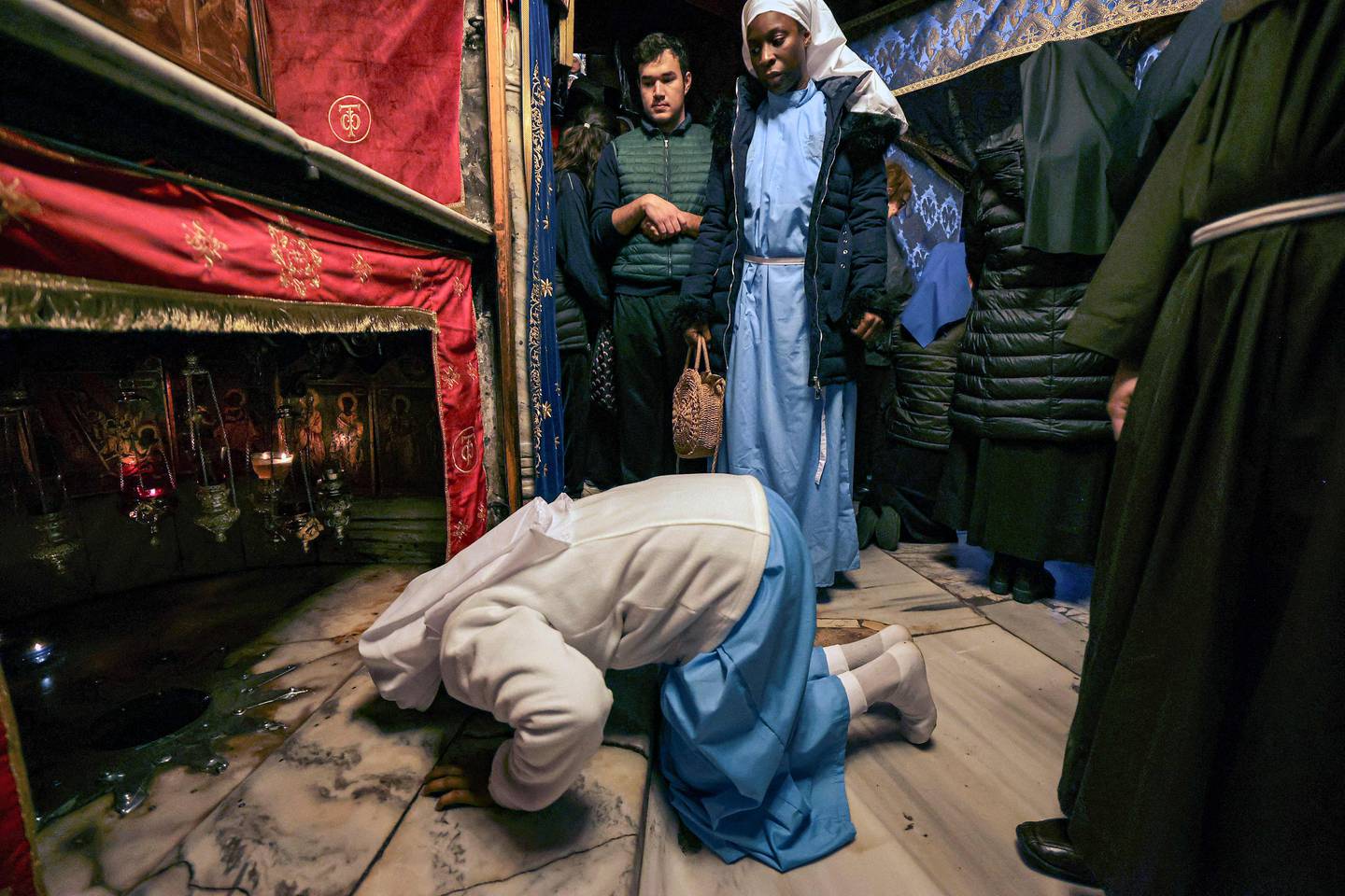 A pilgrim prostrates in prayer before the grotto, believed to be the site of the birth of Jesus, at the crypt of the Church of the Nativity in Bethlehem in the occupied West Bank on Christmas Day on December 25.  AFP
