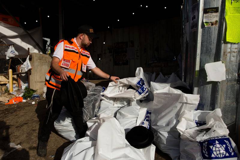A rescue worker collects hats worn by of Orthodox Jews in plastic bags after dozens were killed in crush at religious festival in Mount Meron. Getty Images