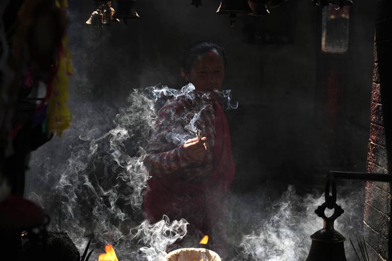 A woman lights incense while offering prayers during the Holi festival in Bhaktapur, Nepal. AP
