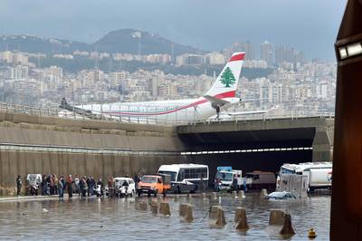 A Middle East Airlines (MEA) plane lands at the airport as vehicles are submerged in water after a heavy downpour on the main road near Rafic Hariri International Airport at the southern entrance of Beirut.  EPA