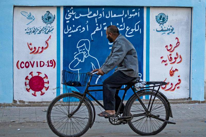 A Syrian man rides a bicycle past a mural painted as part of an awareness campaign by the United Nations International Children's Emergency Fund (UNICEF) and World Health Organization (WHO) intitative, bearing instructions on protection from COVID-19 in the Kurdish-majority city of Qamishli of Syria's northeastern Hasakeh province, after a spike in infections in the area.  AFP