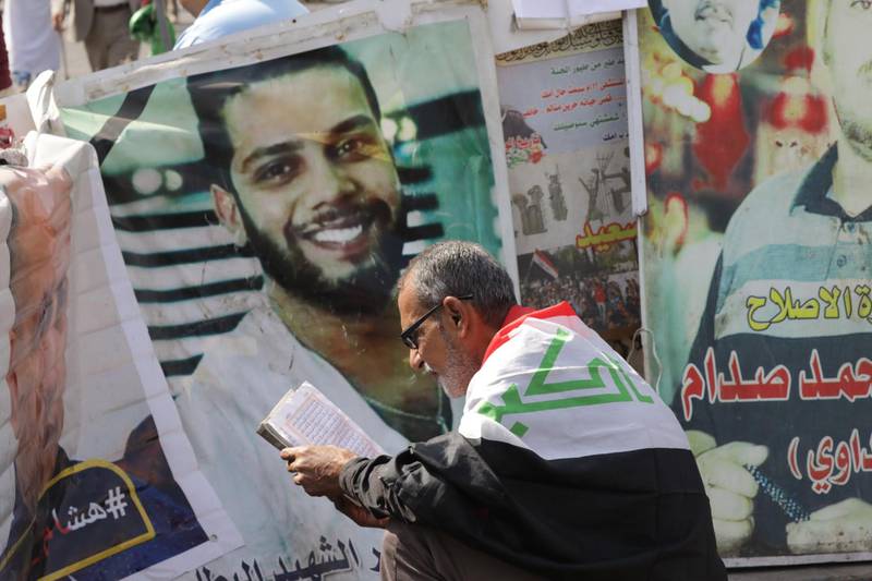 A protester prays next to images of protest victims, as they take part in a demonstration in Tahrir Square in Baghdad. EPA