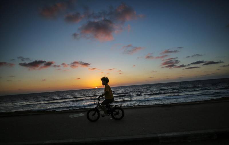 A Palestinian refugee boy rides his bicycle at sunset on the streets of Al Shatea refugee camp, north Gaza City. EPA
