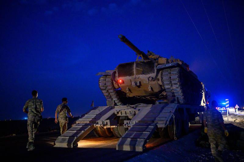 A Turkish army tank drives down from a truck as Turkish armed forces drive towards the border with Syria near Akcakale in Sanliurfa province.  AFP