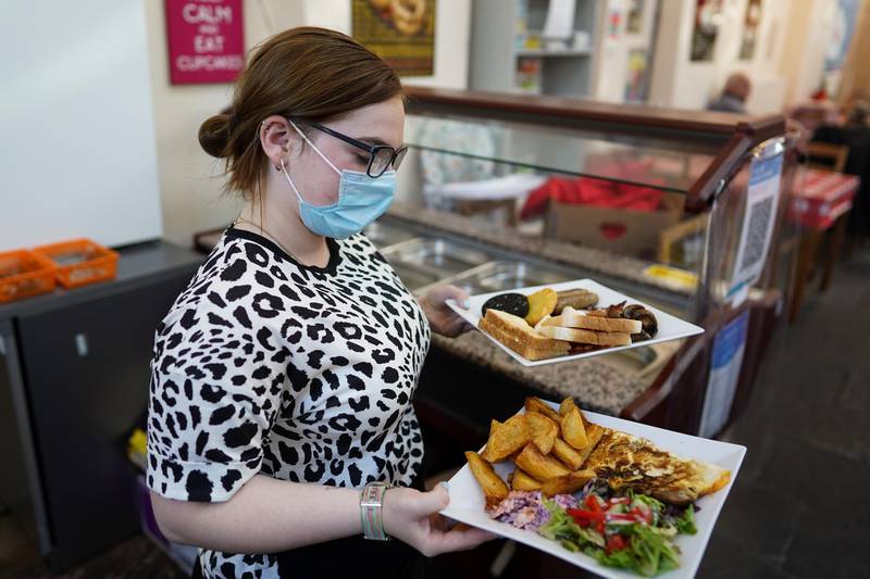 A waitress serves a meal at a cafe in the Richmond Victorian indoor market. The cafe are offering free meals to families in need during the school holidays. Getty Images