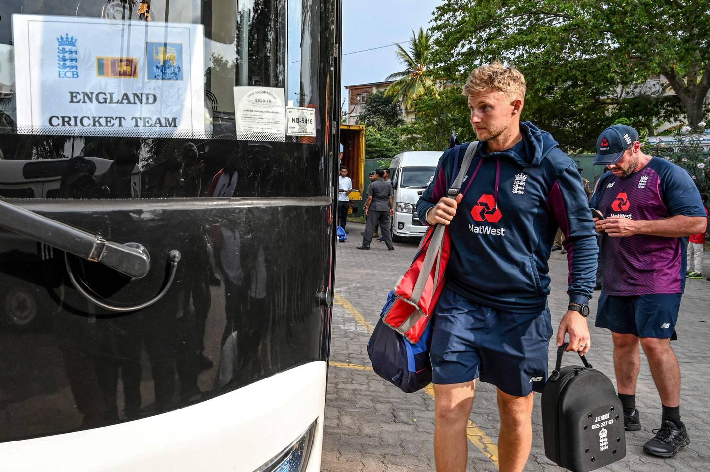 England's captain Joe Root (L) boards the bus after the Test series against Sri Lanka was postponed at the P. Sara Oval Cricket Stadium in Colombo on March 13, 2020.  England's cricket team abruptly pulled out of a tour of Sri Lanka on March 13 over the mounting coronavirus pandemic. A practice match in Colombo was halted as the team announced they would be flying back to London, and the first of two Test matches due to start on March 19 has been postponed. / AFP / LAKRUWAN WANNIARACHCHI

