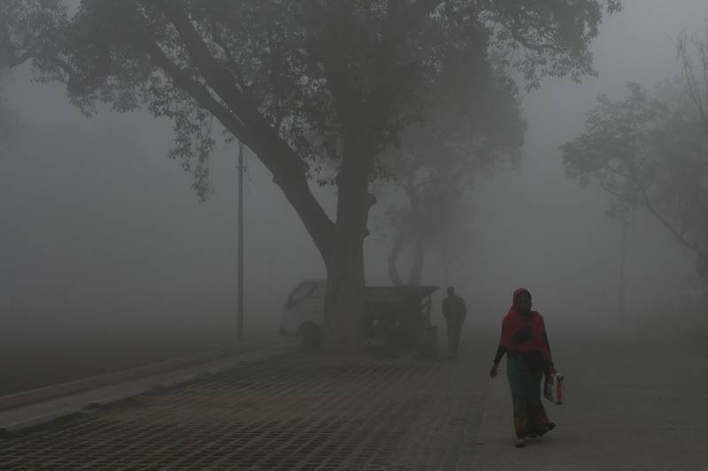 People walk along a road near India Gate amid heavy smog in New Delhi. AFP