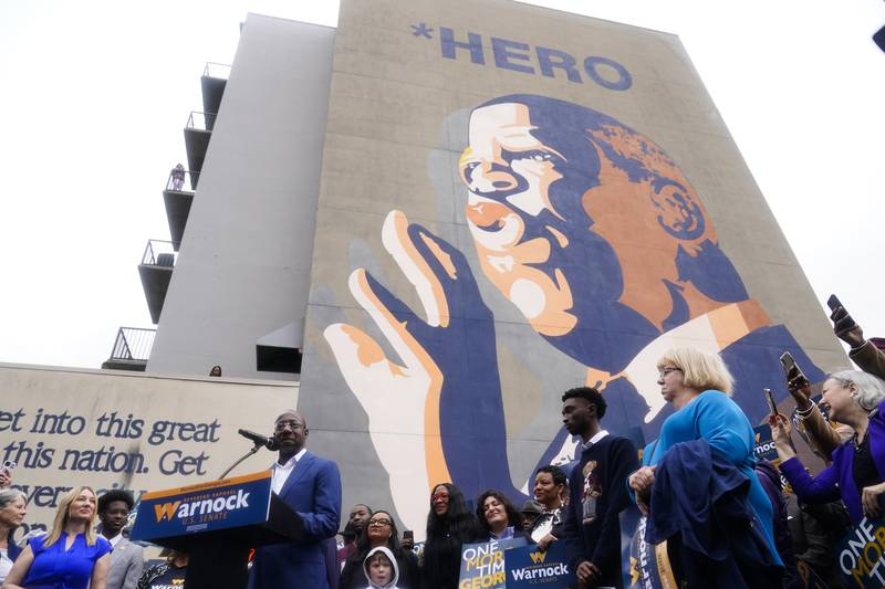 Mr Warnock speaks during a news conference in front of a mural of civil rights leader John Lewis, located down the street from the church where he is pastor. AP