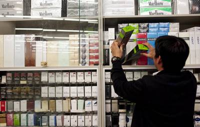 A worker stocks shelves in a Dubai supermarket. Bahrain and Saudi Arabia have introduced additional 'fees' on cigarettes. Sarah Dea / The National