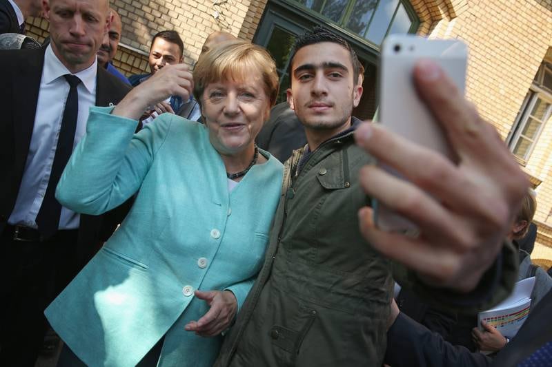 Mrs Merkel poses for a selfie with Anas Modamani, a refugee from Syria, as she visited the AWO Refugium Askanierring shelter for migrants and refugees in September 2015, in Berlin. Getty Images