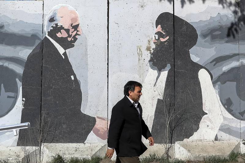 epa09041861 Afghan man passes by a wall painted with a
photo of Zalmay Khalilzad, U.S. special envoy in Afghanistan (L), and Mullah Abdul Ghani Baradar, the leader of the Taliban delegation, on the first anniversary of the agreement between the United States and the Taliban, in Kabul, Afghanistan, 27 February 2021 (issued 28 February 2021). Afghanistan marks the first anniversary of the agreement between the United States and the Taliban that was signed in Doha on 29 February 2020 for bringing Peace to Afghanistan, the withdrawal of US troops and launching intra-Afghan negotiations.  EPA/HEDAYATULLAH AMID