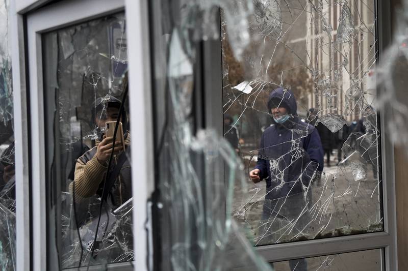 A man takes photos of windows at a police kiosk damaged by demonstrators during a protest in Almaty, Kazakhstan. AP