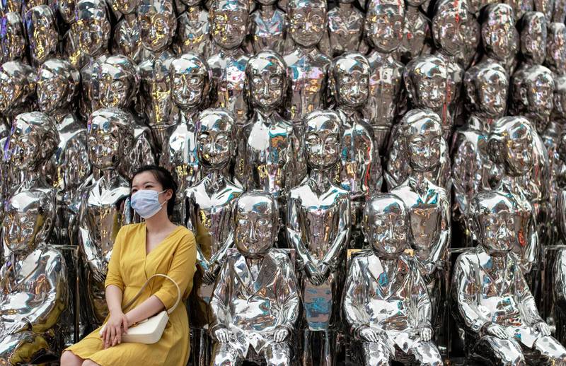 A woman wearing a face mask poses for a picture at a shopping centre in Beijing. AFP