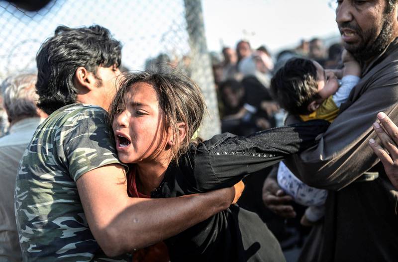 Syrians fleeing the war rush through broken down border fences to enter Turkish territory illegally, near the Turkish border crossing at Akcakale in Sanliurfa province on June 14, 2015. Turkey said it was taking measures to limit the flow of Syrian refugees onto its territory after an influx of thousands more over the last days due to fighting between Kurds and jihadists. Under an "open-door" policy, Turkey has taken in 1.8 million Syrian refugees since the conflict in Syria erupted in 2011. (Photo by BULENT KILIC / AFP)