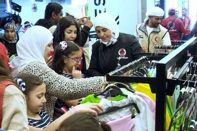 The Emirates Red Crescent team helps children select clothes for Eid