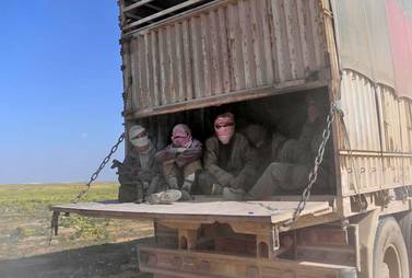 Alleged ISIS fighters and their families sit in the back of a truck as they leave the group's last holdout of Baghouz in Syria's. AFP 