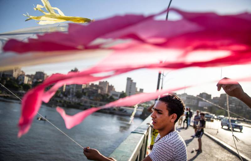 epa08524527 A man pulls a kite to let it fly on a bridge over Nile River in Cairo, Egypt, 30 June 2020 (issued 03 July 2020). Egyptians from all ages take advantage of the spring winds to fly kites of all sizes and colors every year around the same time. The semi-curfew, put in place by the authorities since mid March, to stop the spread of the COVID-19 pandemic, made the hobby even more visible as more people go on their rooftops and streets to play.  EPA/MOHAMED HOSSAM
