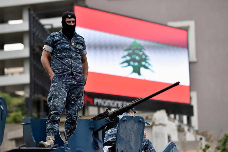 A policeman looks on as he stands on the turret of a military  in Beirut. EPA