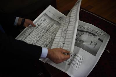 In this photo taken on October 10, 2018, an Afghan employee of the Independent Election Commission (IEC) shows a newspaper-sized ballot paper at a warehouse in Kabul. More than 800 faces, 15 pages, one vote. Kabul voters will wrestle with a newspaper-sized ballot on October 20, racing to find their candidate as quickly as possible under the threat of a militant attack.
 - TO GO WITH: Afghanistan-politics
 / AFP / WAKIL KOHSAR / TO GO WITH: Afghanistan-politics
