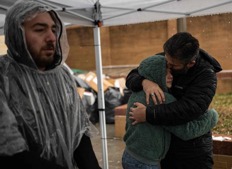 A man hugs his daughter as they take a break from receiving donations for people affected by the earthquake in Turkey. AFP