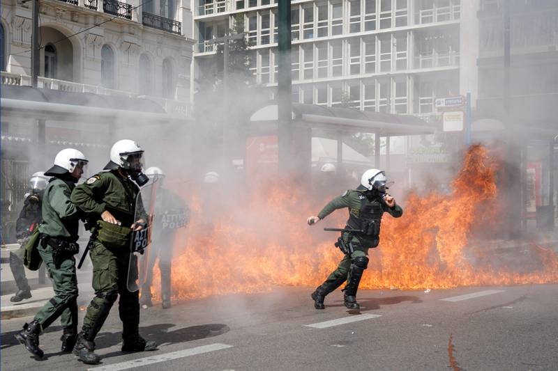 A riot police officer throws a stun grenade in Athens. Reuters