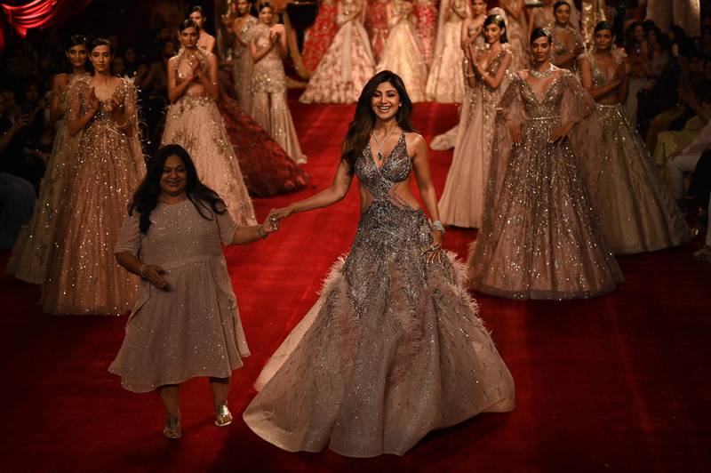 Bollywood actress Shilpa Shetty Kundra (C) walks with Indian fashion designer Dolly J during the FDCI India Couture Week in New Delhi on July 28, 2022.  (Photo by Money SHARMA  /  AFP)  /  IMAGE RESTRICTED TO EDITORIAL USE - STRICTLY NO COMMERCIAL USE -
