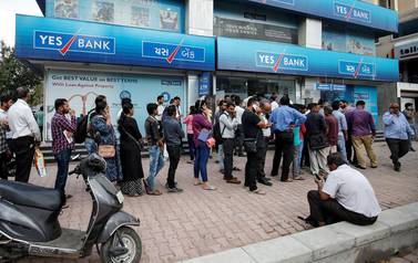 People wait outside a Yes Bank branch to withdraw their money in Ahmedabad - the lender has collapsed heap of bad loans.  Reuters 