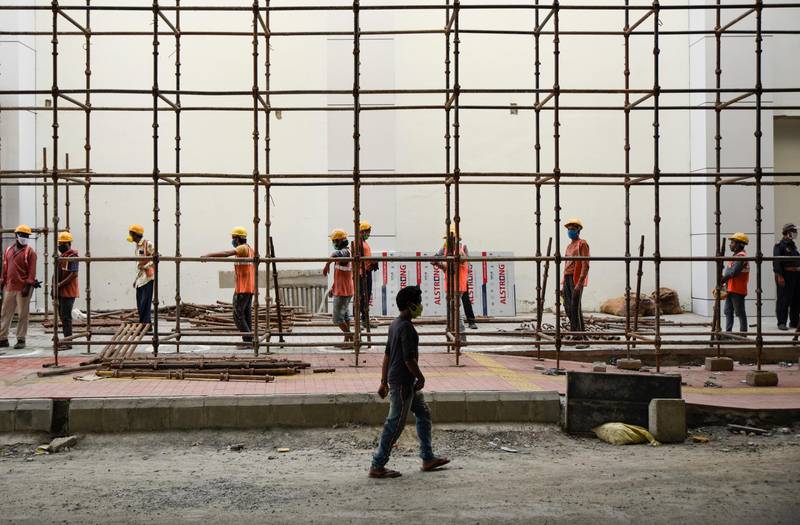 Labourers wearing masks report for the day's work at a metro rail construction site in Kochi, Kerala. AP Photo