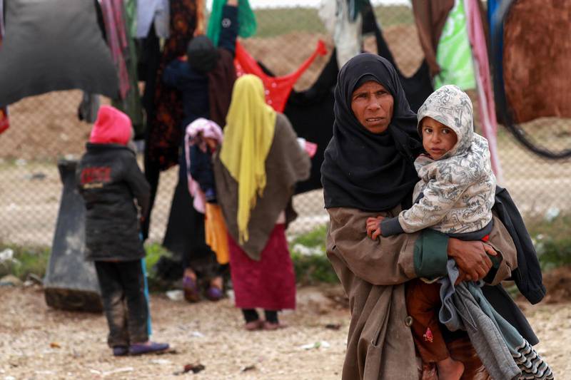 A Syrian displaced woman carries her child inside the Internallly Displaced Persons (IDP) camp of al-Hol in al-Hasakeh governorate in northeastern Syria on December 8, 2018. People from the localities of Hajine, Soussa and al-Shaafa have fled in recent days a pocket held by the Islamic State group (IS) in Syria's eastern province of Deir Ezzor, where the jihadists have fiercely resisted for almost three months in an offensive launched by the Kurdish coalition Arab Syrian Democratic Forces (SDF). / AFP / Delil SOULEIMAN
