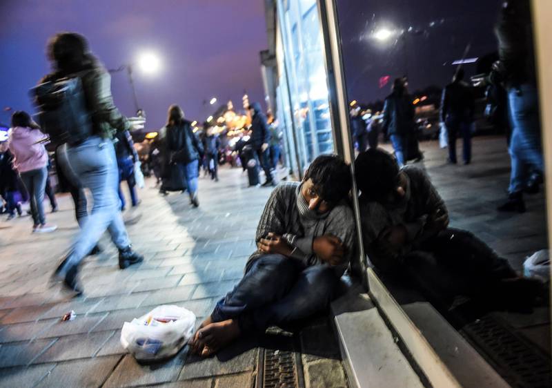 TOPSHOT - A boy sells tissues in front of Kadikoy ferry station at Eminonu during rush hour on December 4, 2018, in Istanbul. / AFP / BULENT KILIC
