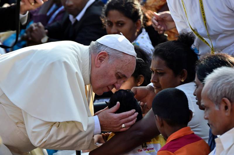 Pope Francis kisses a sick child before a canonisation mass for Joseph Vaz in the Sri Lankan capital Colombo on January 14, 2015. Hundreds of thousands of Sri Lankans crowded the Colombo seafront to take part in a vibrant open-air mass by Pope Francis, in one of the biggest public gatherings the city has ever witnessed. Many worshippers had waited all night for a glimpse of Francis, who canonised Sri Lanka's first saint, the 17th century missionary Joseph Vaz, during the colourful ceremony on Colombo's imposing Galle Face Green overlooking the Indian Ocean. AFP PHOTO /GIUSEPPE CACACE (Photo by GIUSEPPE CACACE / AFP)