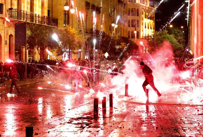 Anti-government protesters throw firecrackers at riot police during a demonstration against the new government, near Parliament Square, in Beirut, Lebanon. AP Photo
