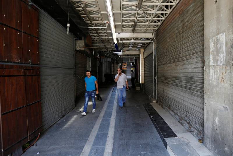People walk next to a shop closed during the strike. Muhammad Hamed / Reuters