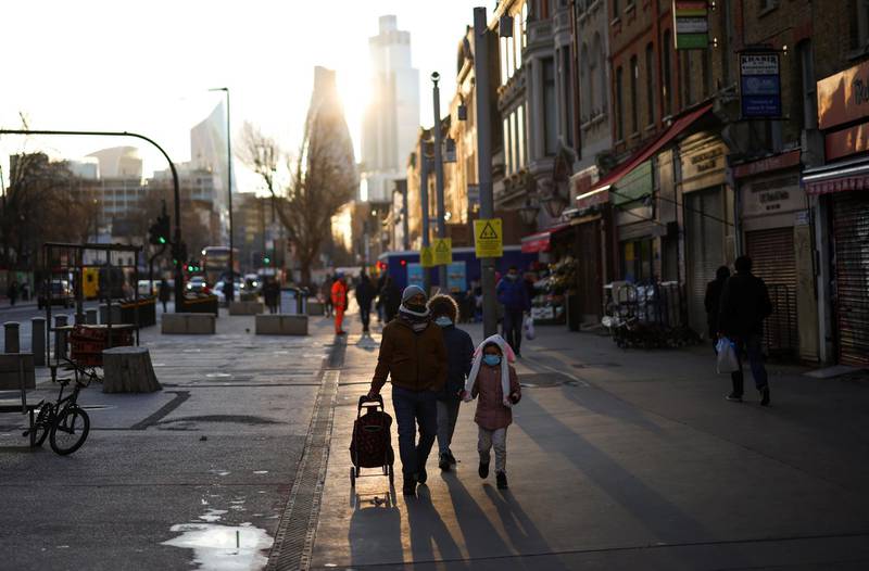 People walk past shops and market stalls in east London. Reuters