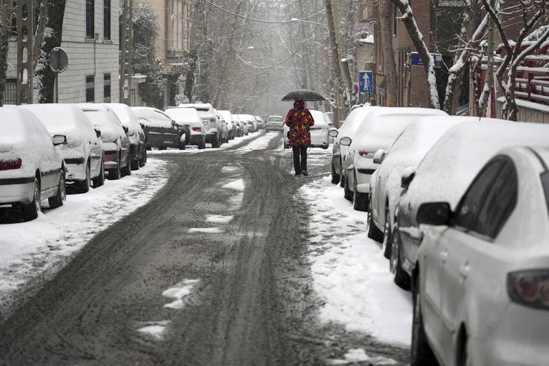 A pedestrian in Tehran keeps to the roads where heavy snow turns to slush. AP