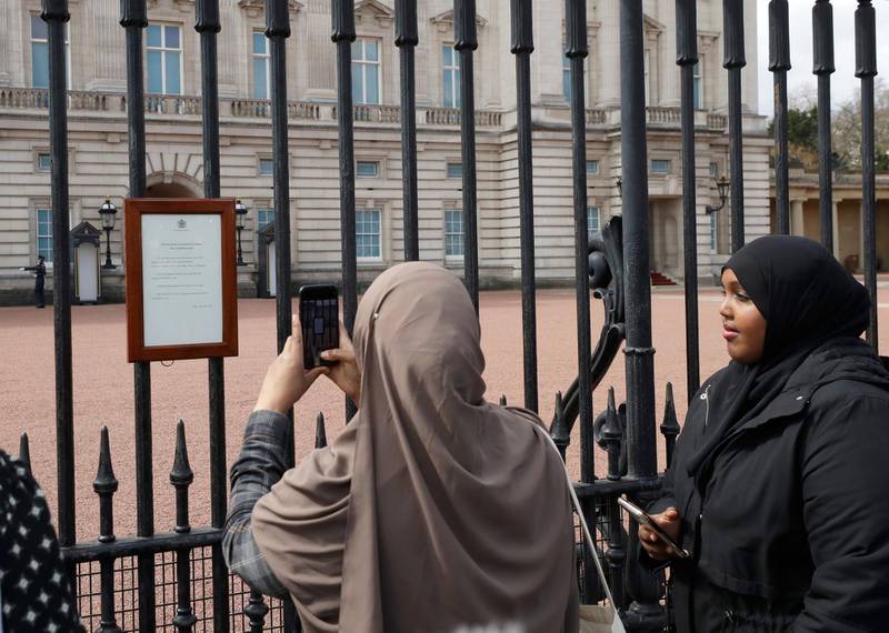 People take pictures of the announcement displayed on the fence of Buckingham Palace. AP Photo