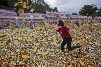 An ethnic Chinese woman throws imitation money during the festival in Medan, Indonesia. AP