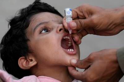 A health worker administers a polio vaccine to a child at a railway station in Karachi, Pakistan. AP