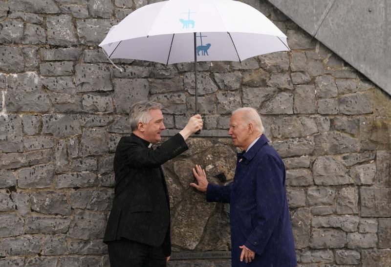 Präsident Joe Biden berührt mit Vater Richard Gibbons in der Grafschaft Mayo, Irland, die ursprüngliche Giebelwand der Kirche am Knock Shrine.