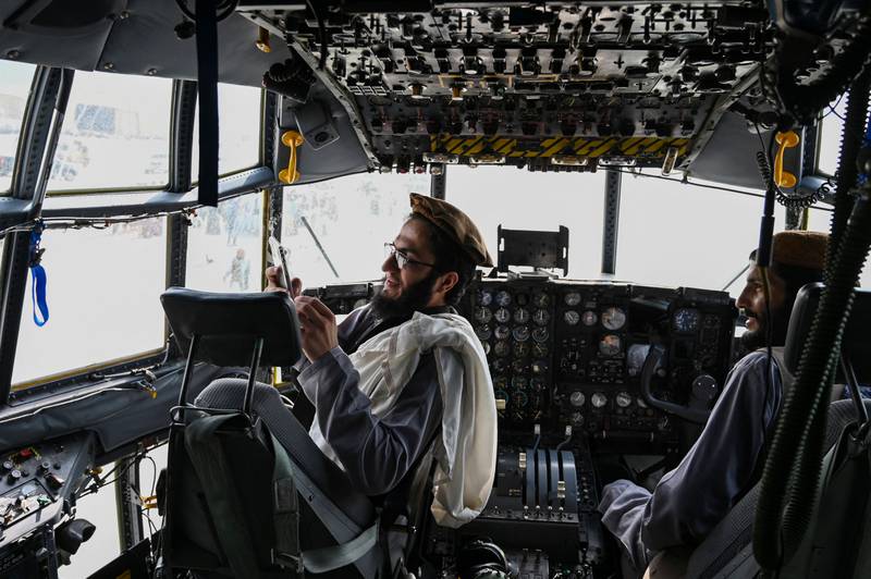 Taliban fighters sit in the cockpit of an Afghan Air Force aircraft at the airport in Kabul. AFP