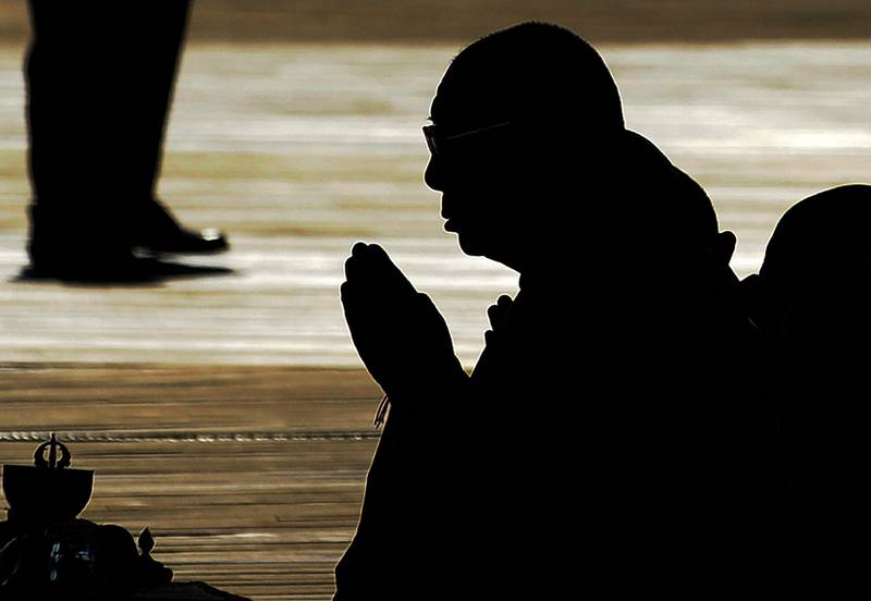 Tibetan spiritual leader the Dalai Lama (C) is silhouetted as he prays before blessing the Anacostia River in Washington with sand from a mandala mixed with water during a ceremony marking the end of the annual Kalachakra on July 16, 2011.  US President Barack Obama on Saturday defied warnings from China and welcomed the Dalai Lama to the White House, urging respect for human rights and cultural traditions in Tibet.  China immediately lodged a protest and accused Obama of undermining relations between the world's two largest economies by meeting with Tibet's exiled spiritual leader, who has spent more than a half-century in exile.  AFP Photo / Jewel SAMAD
 *** Local Caption ***  434867-01-08.jpg