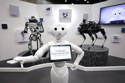 A SoftBank Group Corp. Pepper humanoid robot, center, stands in front of a Boston Dynamics Inc. Atlas humanoid robot, left, and Spot robot as they are displayed at the SoftBank Robot World 2017 in Tokyo, Japan, on Tuesday, Nov. 21, 2017. SoftBank Chief Executive Officer Masayoshi Son has put money into robots, artificial intelligence, microchips and satellites, sketching a vision of the future where a trillion devices are connected to the internet and technology is integrated into humans. Photographer: Kiyoshi Ota/Bloomberg