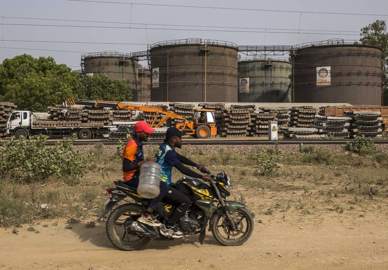 A motorcyclist rides past an oil depot in New Delhi. India's heavy dependence on commodity imports such oil, combined with elevated prices, are contributing to the country's widening trade deficit. Bloomberg