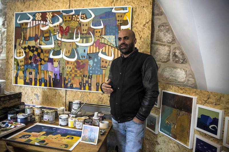 Palestinian artist Ayed Arafah as he speaks to visitors on a tour in his studio in the West Bank city of Beit Sahour.

A recurrent image in his painting is the bull. In one painting  bulls are interspersed with butterflies. "In this series I tried to pose myself as a bull, which feels it is created to  be like a warrior and is facing other warriors so he's expected to be a hard fighter. But I take him out of the zone of fighting and have him just doing daily stuff because the Palestinians are stereotyped to be fighters and this is turning us to not be human beings."he says.
(Photo by Heidi Levine for The National).