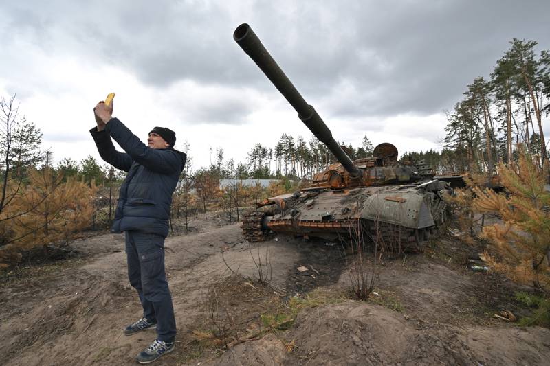A man takes a selfie in front of a destroyed Russian tank in the village of Andriivka, Ukraine, on April 17. AFP