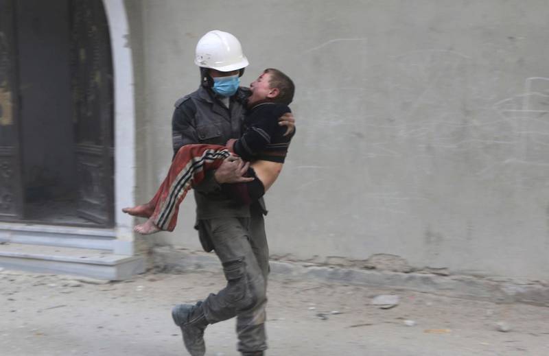 A member of the Syrian Civil Defence group carries a boy away from the shelling. Syrian Civil Defense White Helmets via AP