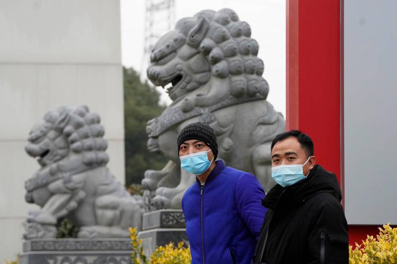 Chinese men wearing masks stand near stone lions across from the Wuhan Jinyintan Hospital where a team from the World Health Organization visited in Wuhan in central China's Hubei. AP Photo