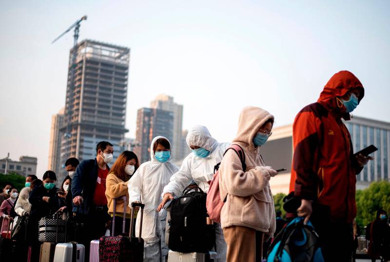 People wearing face masks arrive at Hankou Railway Station in Wuhan to take one of the first trains leaving the city.  AFP