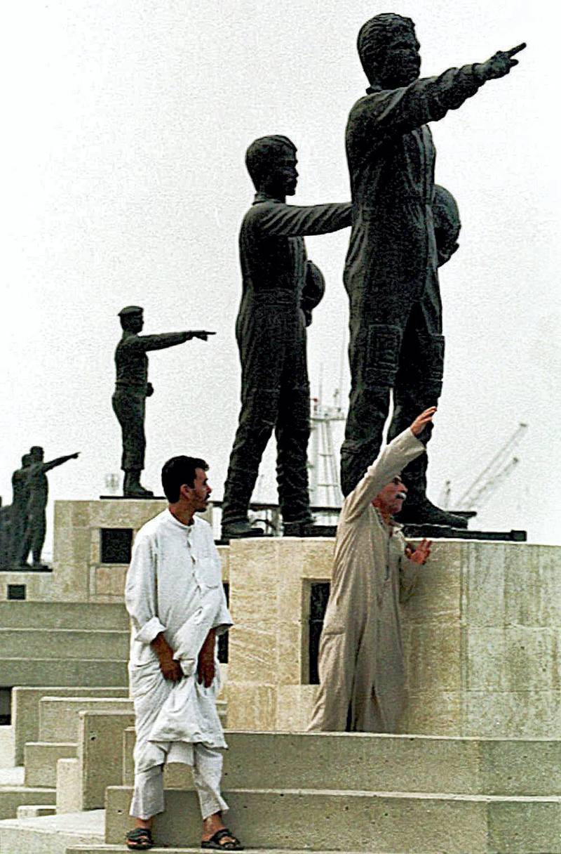Two Iraqi citizens pass by statues representing Iraq's martyrs from the 1991 Gulf War, 13 May 1999 in the southern city of Basra. (Photo by KARIM SAHIB / AFP)